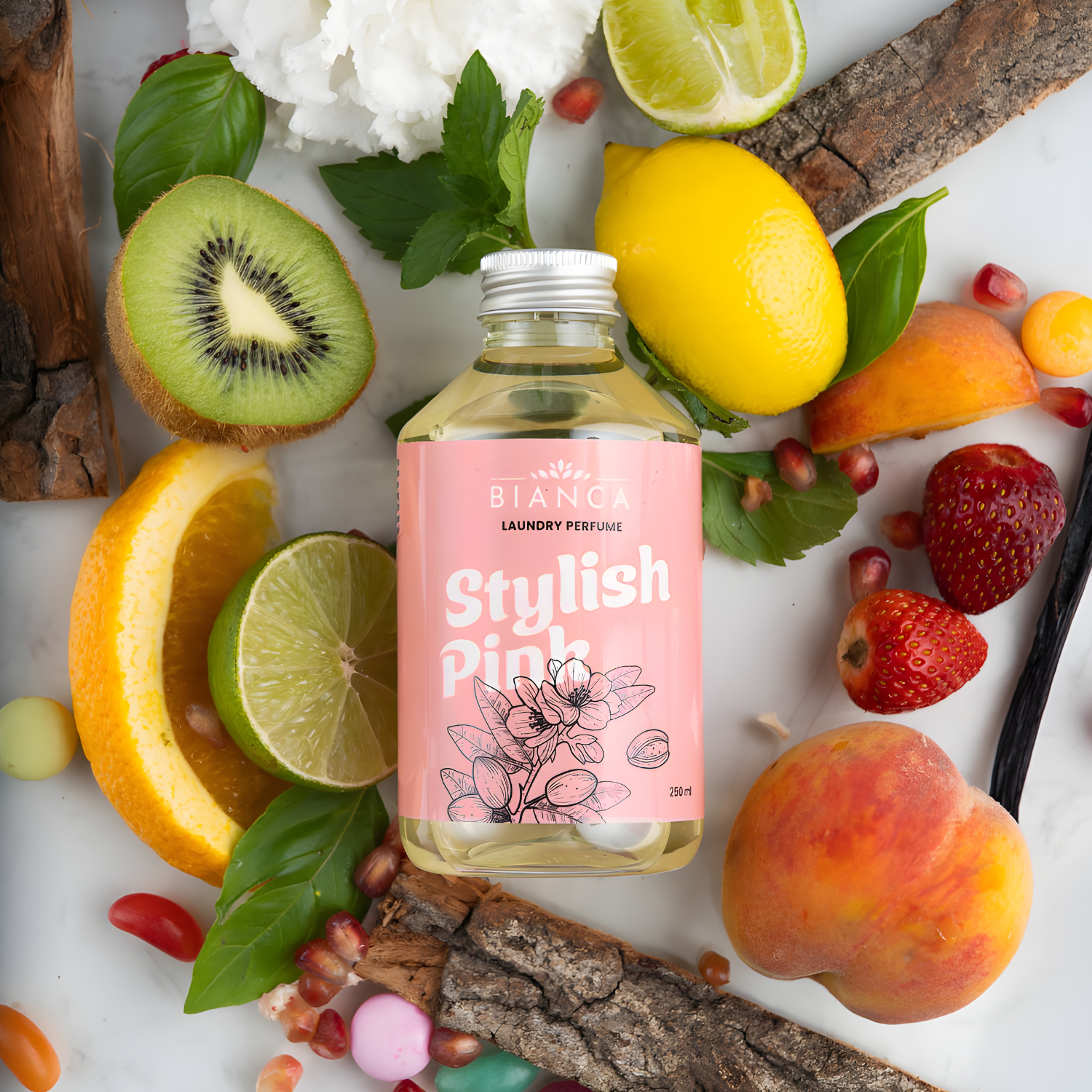Stylish Pink laundry perfume bottle surrounded by kiwi, lime, lemon, peach, strawberries, and floral notes.